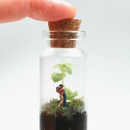 Terrario amuleto ‘el beso’  - Jardín miniatura en botella de vidrio con figura de hombre y mujer dándose un beso.
